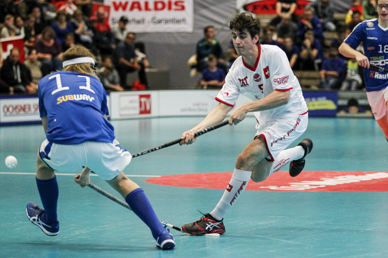 Nadir Monighetti (Nr. 5, Schweiz U19) mit einem Abschluss und steht dabei auf Niko Uurtio(Nr. 11, Finnland U19)'s Kelle.

4.11.2017; Schweden U19 - Tschechien U19, Sporthalle Grossmatt; Kirchberg)
Photos: www.unihockey-fotos.ch Claudio Thoma