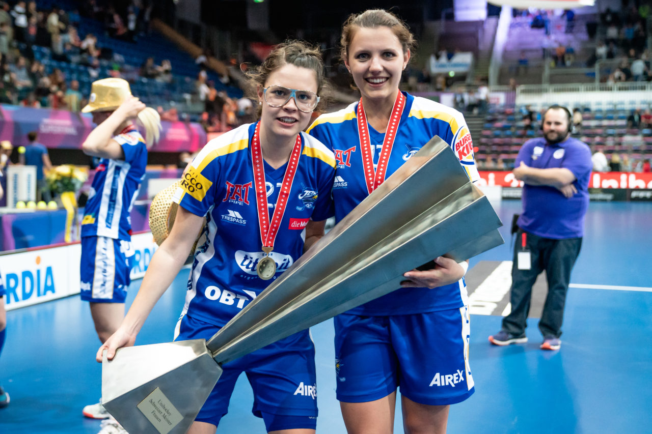 SWISS Arena (Kloten), 27.04.2019, Unihockey Damen NLA Superfinal, piranha chur - Kloten-Dietlikon Jets, Isabelle Gerig (Nr. 23, Kloten-Dietlikon Jets) und Linda Pedrazzoli (Nr. 13, Kloten-Dietlikon Jets) mit dem Pokal
(Claudio Schwarz, unihockey-fotos.ch)
Copyright: Claudio Schwarz, unihockey-fotos.ch – Dieses Bild wurde durch swiss unihockey lizenziert und darf ausschliesslich auf den Online-Kanälen von swiss unihockey verwendet werden. Die redaktionelle oder kommerzielle Nutzung durch Dritte (Medien, Vereine, Unternehmen oder Privatpersonen) per Download von diesem flickr-Account ist ausgeschlossen. Das Bild kann bei Interesse via unihockey-fotos.ch kostenpflichtig lizenziert werden. unihockey-fotos.ch behält sich vor, fehlbaren Medien, Vereinen, Unternehmen oder Privatpersonen Bilder mit einem Zuschlag in Rechnung zu stellen.